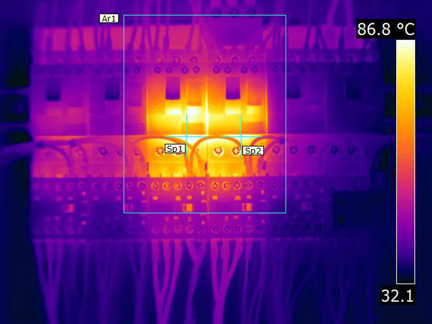 FLIR thermal image of a low-voltage board where two contactors glow at 86.8 degrees against a 32 degree background