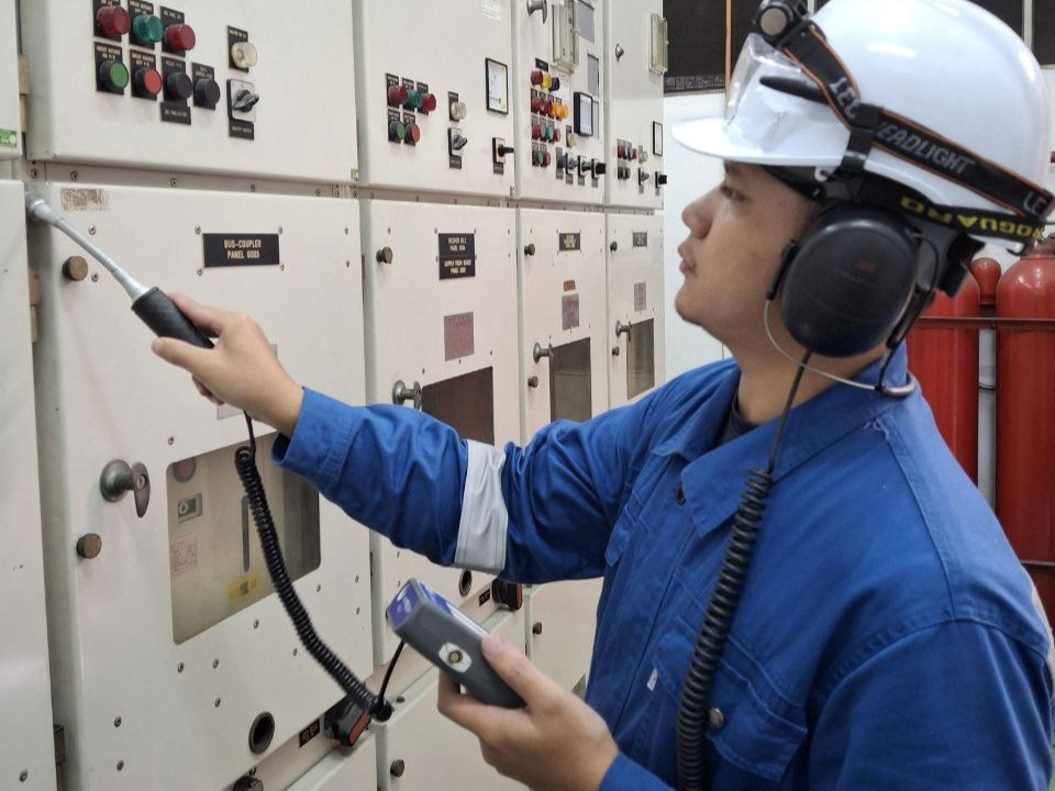 An AMKA technician wearing headphones and using a flexible ultrasonic probe to survey closed live switchgear for partial discharge